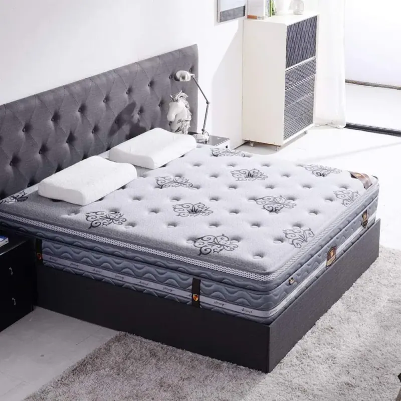 Grey patterned quilted mattress on a bed with a tufted grey headboard